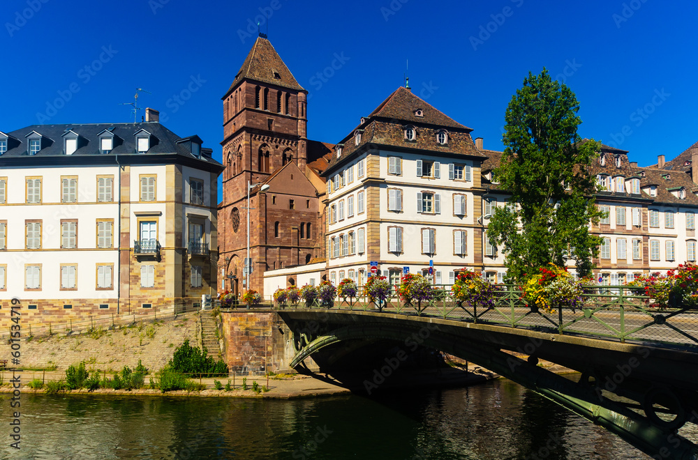 Scenic view of Strasbourg cityscape on sunny summer day overlooking historical building of St Thomas Church on bank of Ill river