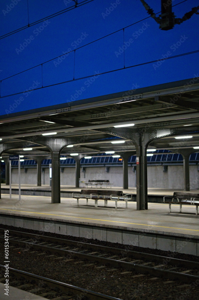 Pusty peron na dworcu kolejowym oświetlony lampami na tle nocnego nieba