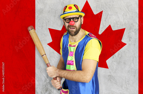 Obraz na plátne An insecure clown holds a bat in his hands against the background of the flag of
