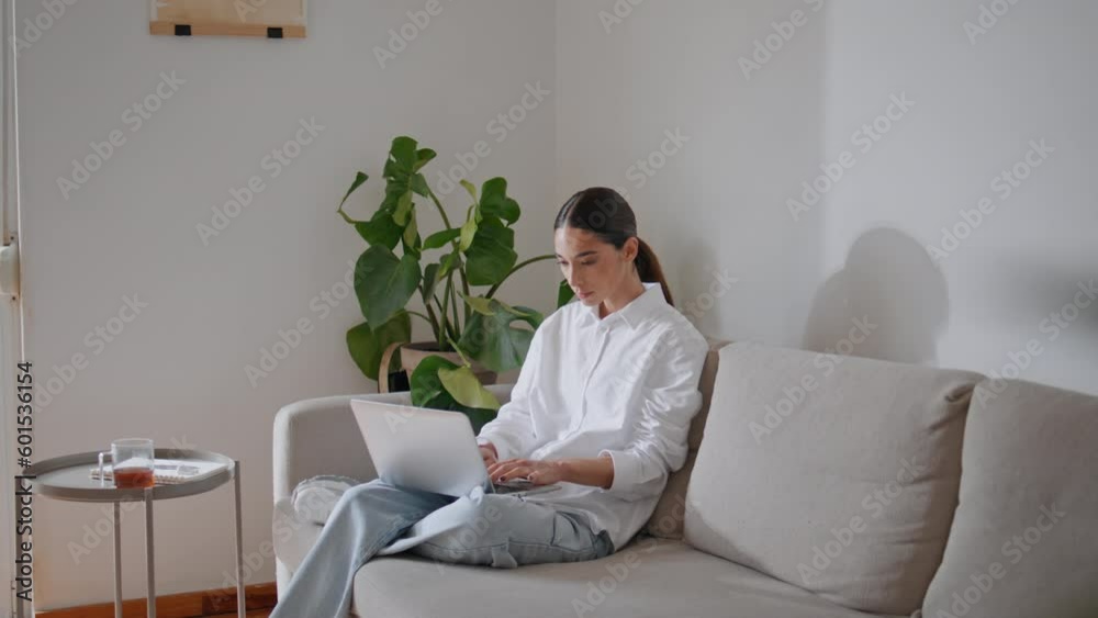 Focused businesswoman typing laptop home couch. Relaxed girl chatting computer Focused businesswoman typing laptop home couch. Relaxed girl chatting computer