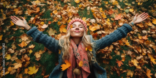 Young beautiful woman with long blonde hair and knitted hat lying down on autumn leaves