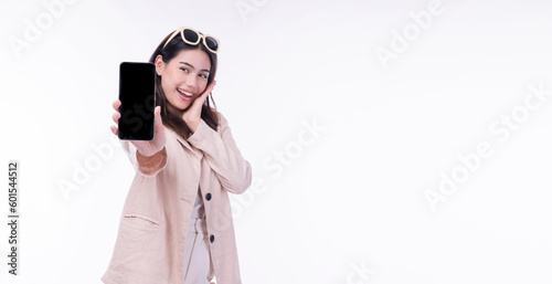 Cheerful excited asian woman sunglasses showing mobile phone empty screen standing on isolated white background. Businesswomen wear suit holding smartphone looking camera. Technology app on cellphone