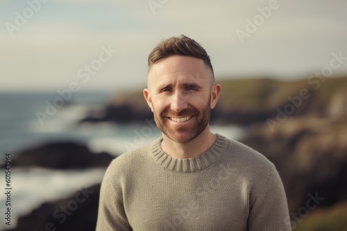 Portrait of handsome man smiling at camera while standing by the sea