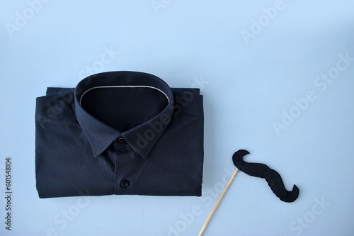 Conceito de celebração do dia dos pais. Vista superior plana de camisa elegante bigode de papel preto  presente em fundo azul claro com espaço vazio para mensagem de saudação photo