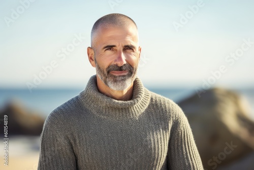 Portrait of smiling mature man looking at camera on beach in autumn
