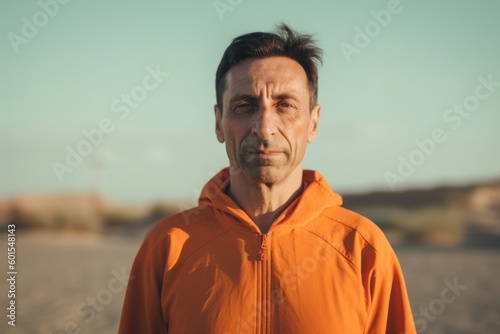 Portrait of a man in an orange jacket on the beach.