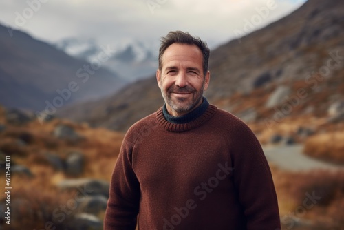 Handsome man in a brown sweater on the background of mountains