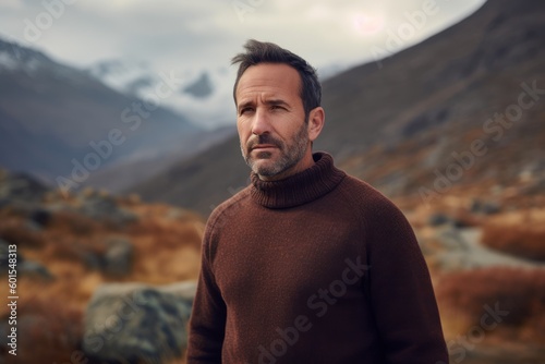 Portrait of a handsome man in a brown sweater against the background of mountains