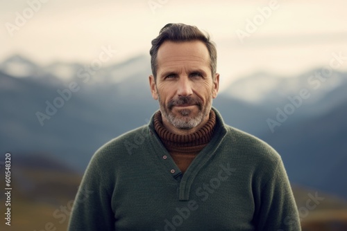 Handsome middle-aged man in a green sweater on a background of mountains