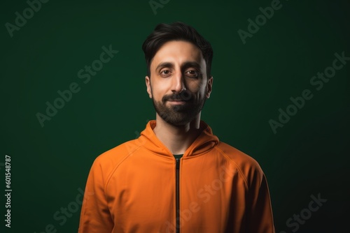 Portrait of a young man in an orange hoodie on a green background © Hanne Bauer