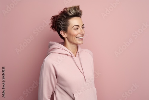 Portrait of a beautiful young woman in a pink hoodie on a pink background