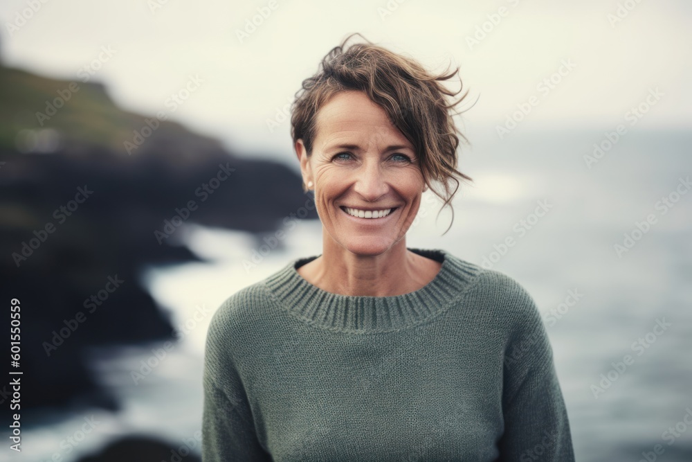 Portrait of smiling mature woman standing in front of ocean at coastline