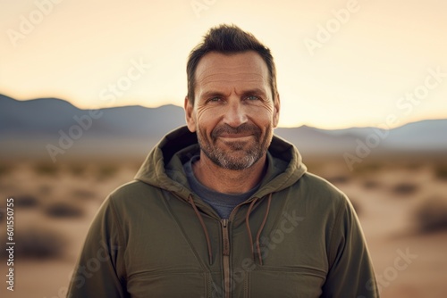 Medium shot portrait photography of a pleased man in his 40s wearing a stylish hoodie against a desert background. Generative AI