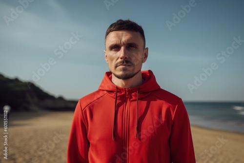 Portrait of handsome young man in red sportswear on the beach.