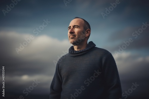 Portrait of a handsome man in a blue sweater on a cloudy sky background