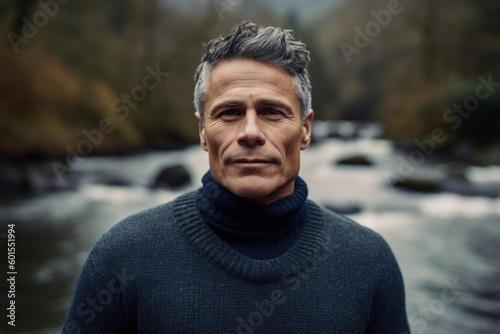 Portrait of a middle-aged man in a sweater on the background of a mountain river.