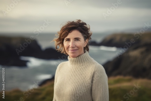 Portrait of smiling mature woman standing in front of camera at coastline