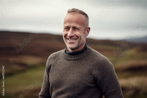 Handsome middle aged man smiling at the camera while standing outdoors.