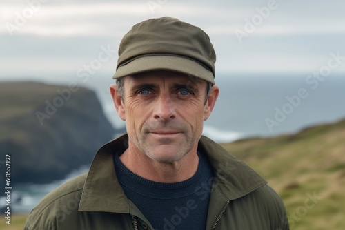 Medium shot portrait photography of a pleased man in his 40s wearing a cool cap or hat against a windswept or dramatic landscape background. Generative AI © Anne-Marie Albrecht
