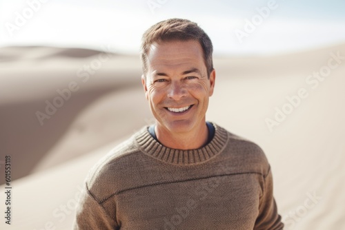 Portrait of smiling man sitting on sand dune in the desert © Anne-Marie Albrecht