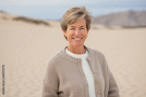 Portrait of smiling senior woman standing in dunes at the beach