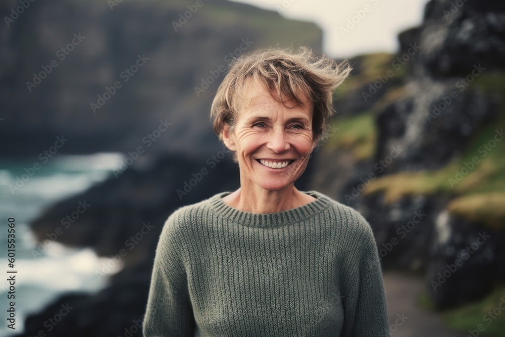 Portrait of smiling mature woman standing in front of cliffs on Atlantic ocean Portrait of smiling mature woman standing in front of cliffs on Atlantic ocean