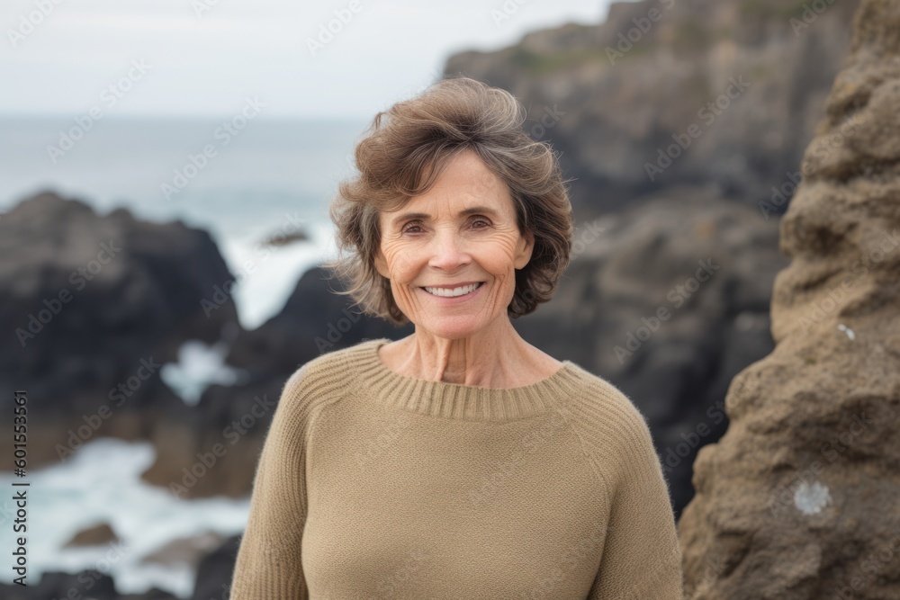 Portrait of smiling senior woman standing in front of rocks at coastline Portrait of smiling senior woman standing in front of rocks at coastline