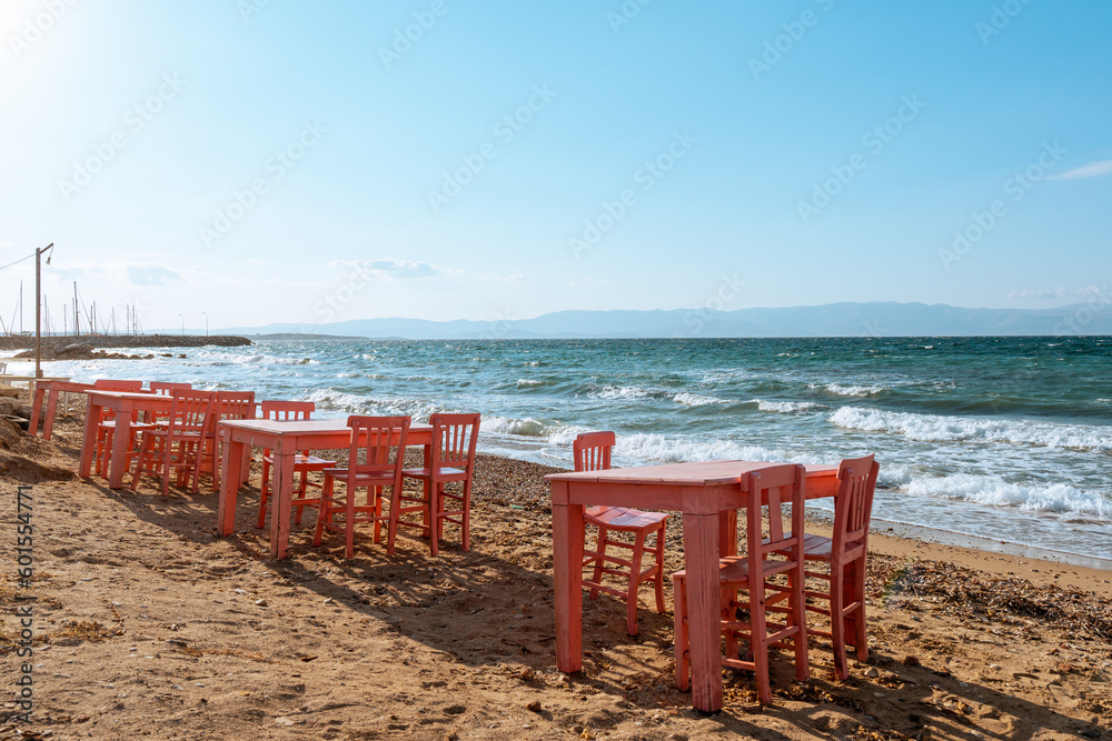 Empty pink chairs and tables on the sea shore