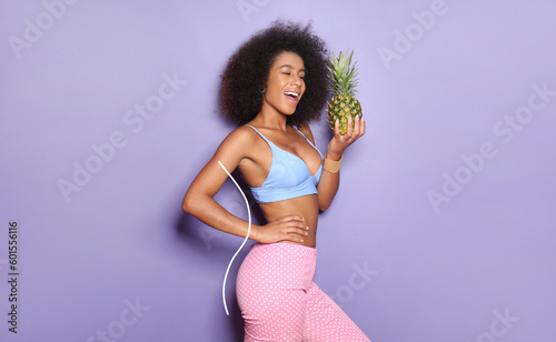 Beautiful African-American woman with pineapple on lilac background. Diet concept