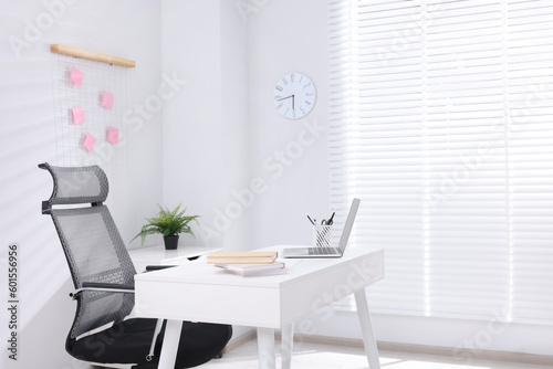 Desk and comfortable chair in modern office, space for text. Interior design