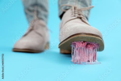 Person stepping into chewing gum on light blue background, closeup