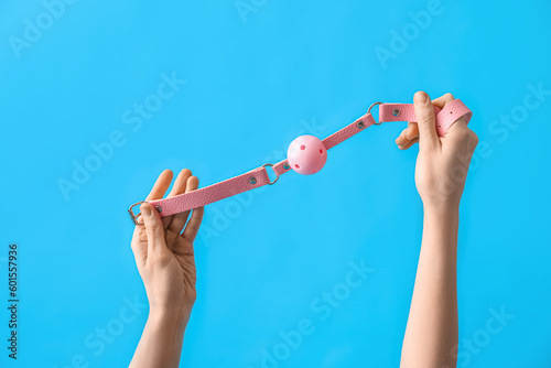 Woman with pink mouth gag from sex shop on blue background