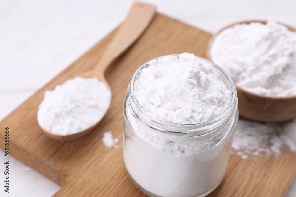 Jar and spoon of starch on wooden board, closeup Jar and spoon of starch on wooden board, closeup