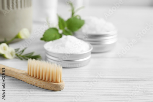 Toothbrush, dental products and herbs on white wooden table, closeup. Space for text