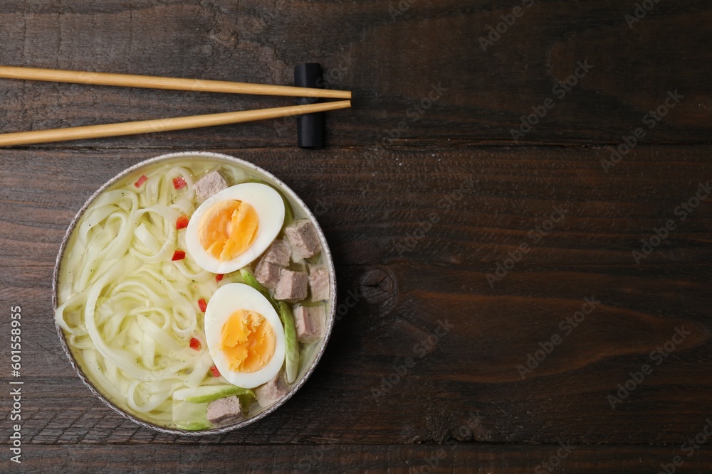 Bowl of delicious rice noodle soup with meat and egg on wooden table, flat lay. Space for text Bowl of delicious rice noodle soup with meat and egg on wooden table, flat lay. Space for text