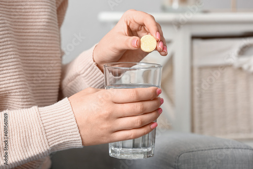 Woman putting effervescent tablet into glass of water