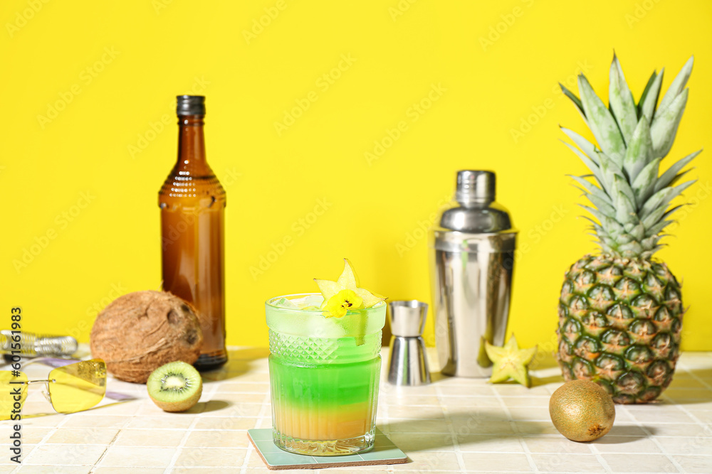 Fresh summer cocktail with carambola on tile table near yellow wall Fresh summer cocktail with carambola on tile table near yellow wall
