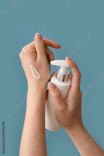 Hands of woman applying cream against blue background