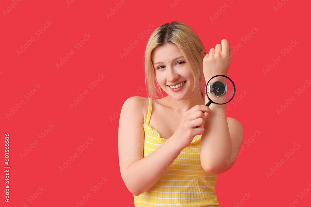 Young woman with magnifier and wristwatch on red background Young woman with magnifier and wristwatch on red background