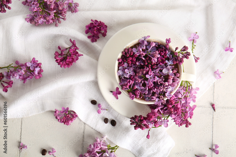 Composition with cup of beautiful lilac flowers and napkin on light table Composition with cup of beautiful lilac flowers and napkin on light table
