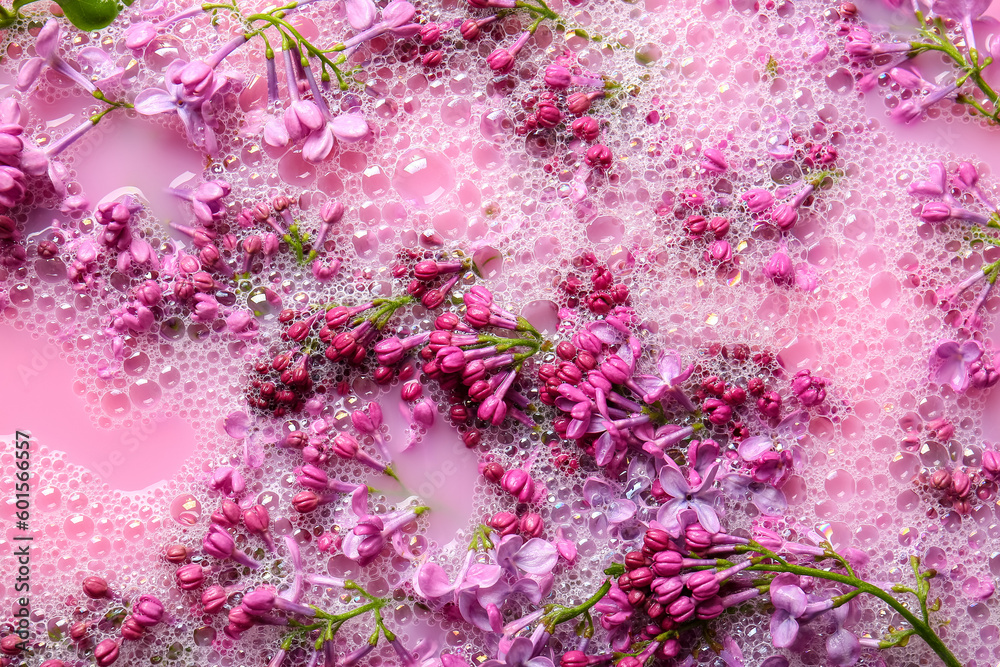 Lilac flowers in pink liquid with soap bubbles, closeup
