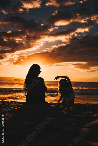 Fotobehang Mother with her daughter enjoying the beautiful orange sunset on the beach on Mo