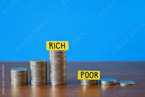Large growing stacked coins opposite a small shrinking stack of coins illustrating the Rich versus the Poor blue background copy space 
