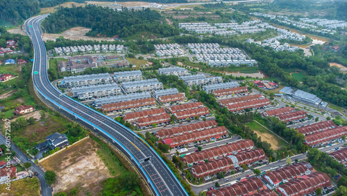 Aerial view of residential area with green asphalt road and residential houses directly above viewpoint. View of suburbs and city district. Real estate and housing market concept.