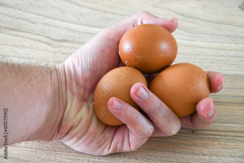 Hand holding three eggs on wooden table