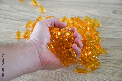 Hand holding many omega 3 pills