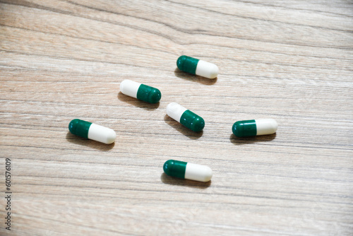 Green and white pills on a wooden table