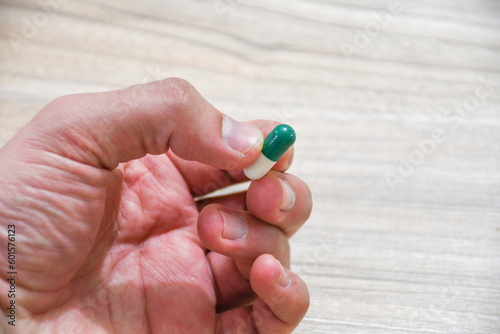 Hand holding green and white pill
