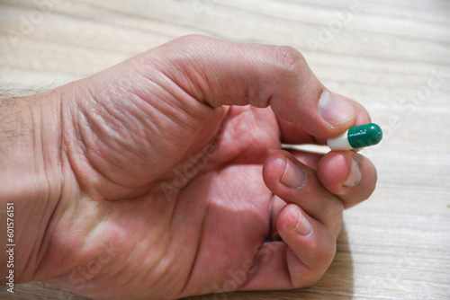 Hand holding green and white pill