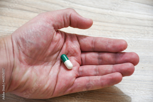 Hand holding green and white pills